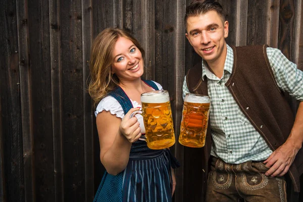 木製の背景にビールグラスを持つ若い女性と男性 オクトーバーフェストのコンセプト — ストック写真