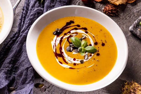 Pumpkin soup in a bowl with pumpkin seeds. Fall dinner.