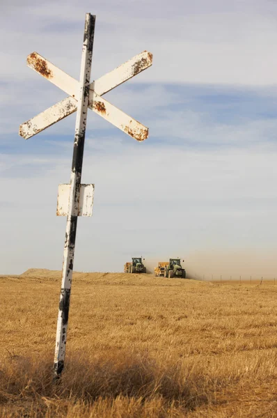 Аграрные тракторы на поле с железнодорожным знаком . — стоковое фото