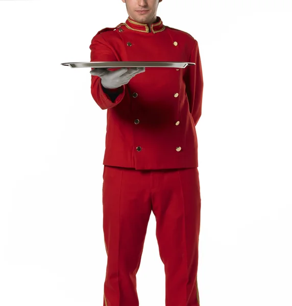 Bellhoper with red uniform presents a tray. — Stock Photo, Image