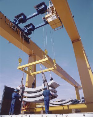 Overhead travelling crane with workers and precast segments. clipart