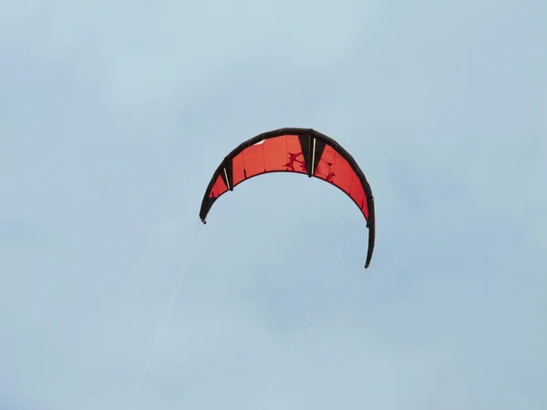 Röd kite surfa under en blå himmel — Stockfoto