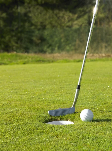 Clube de golfe e uma bola perto do buraco — Fotografia de Stock