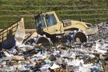 Açık hava atık sahasında çöp öğüten ağır makineler. İsraf.