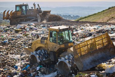 Heavy machinery shredding garbage in an open air landfill. Waste