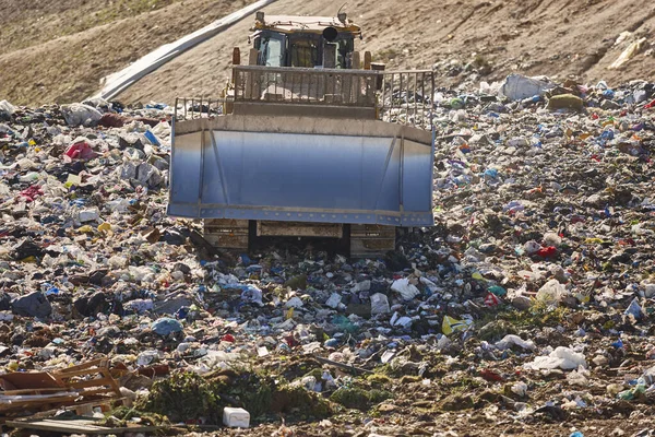 Açık hava atık sahasında çöp öğüten ağır makineler. İsraf.