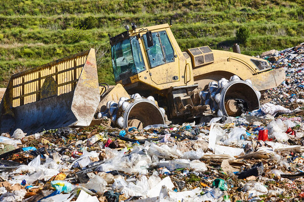 Heavy machinery shredding garbage in an open air landfill. Pollution