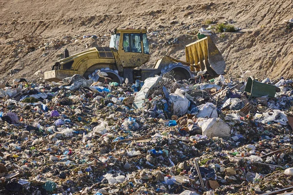Açık hava atık sahasında çöp öğüten ağır makineler. İsraf.