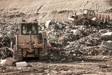 Heavy machinery shredding garbage in an open air landfill. Waste