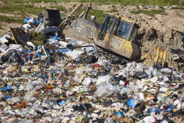 Açık hava atık sahasında çöp öğüten ağır makineler. İsraf.