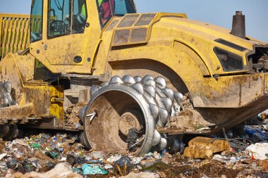 Açık hava atık sahasında çöp öğüten ağır makineler. İsraf.