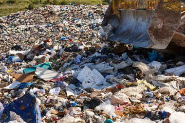 Açık hava atık sahasında çöp öğüten ağır makineler. İsraf.