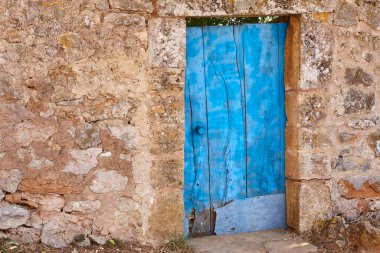 Grunge wooden blue door and stone wall in Mallorca island. Spain