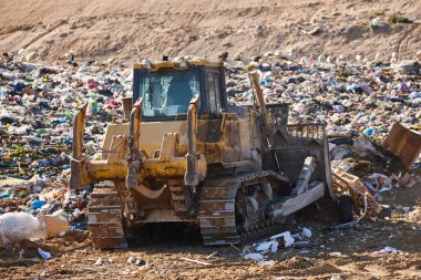 Heavy machinery shredding garbage in an open air landfill. Waste