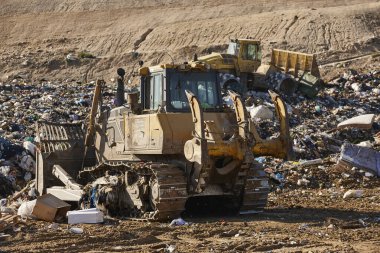 Heavy machinery shredding garbage in an open air landfill. Waste