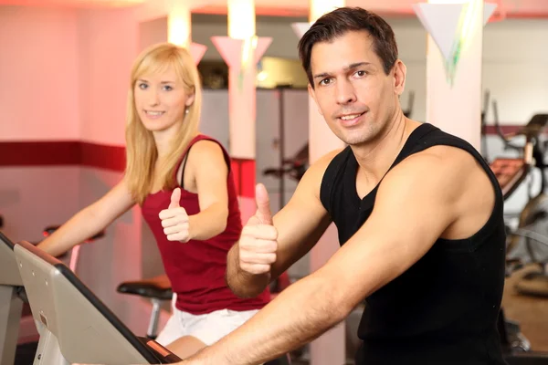 Donna attraente e un uomo in bicicletta in una palestra — Foto Stock