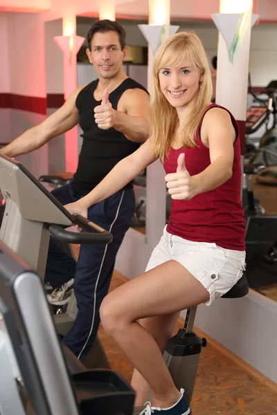 Atractiva mujer y un hombre en bicicleta en un gimnasio —  Fotos de Stock