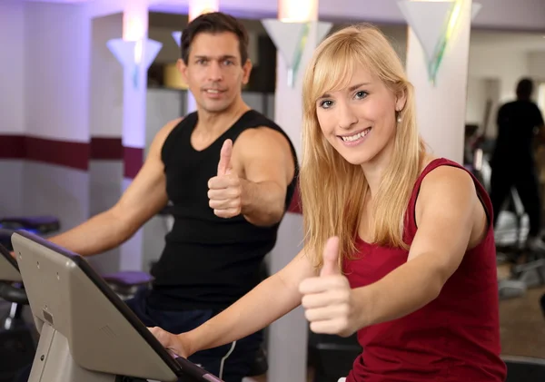 Attractive woman and a man cycling in a gym — Stock Photo, Image