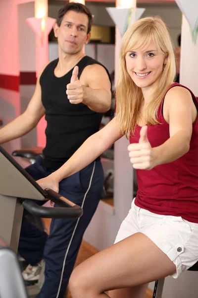 Attractive woman and a man cycling in a gym — Stock Photo, Image