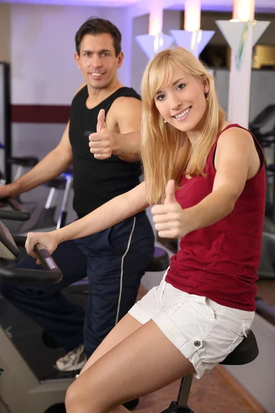 Donna attraente e un uomo in bicicletta in una palestra — Foto Stock