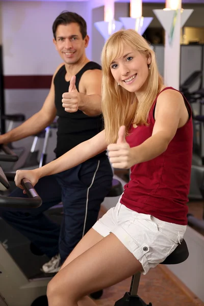 Attractive woman and a man cycling in a gym — Stock Photo, Image