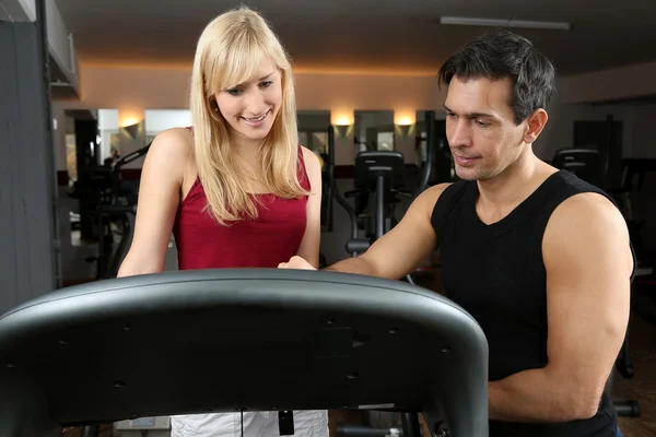 Attractive blonde woman and her trainer in a gym — Stock Photo, Image