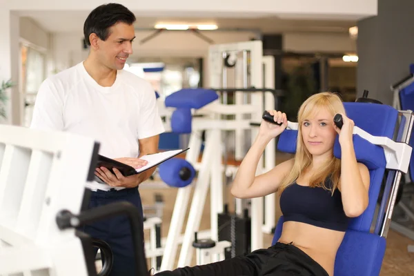 Attractive blonde woman and her trainer in a gym — Stock Photo, Image
