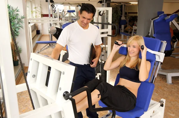 Attractive blonde woman and her trainer in a gym — Stock Photo, Image