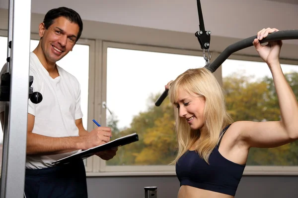 Atractiva mujer rubia y su entrenador en un gimnasio — Foto de Stock