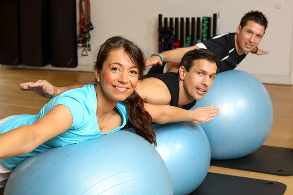 Dos hombres y una mujer haciendo ejercicio sobre bolas de gimnasia — Foto de Stock
