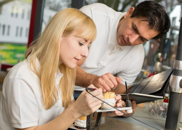 Ausbilder unterrichtet Lehrling im Dentallabor — Stockfoto