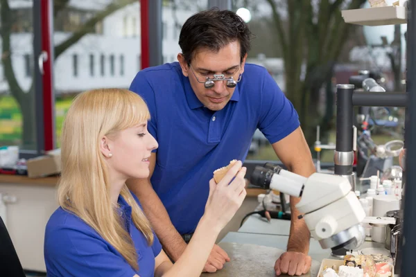 Dental technician showing a prosthesis to a collegue — Stock Photo, Image