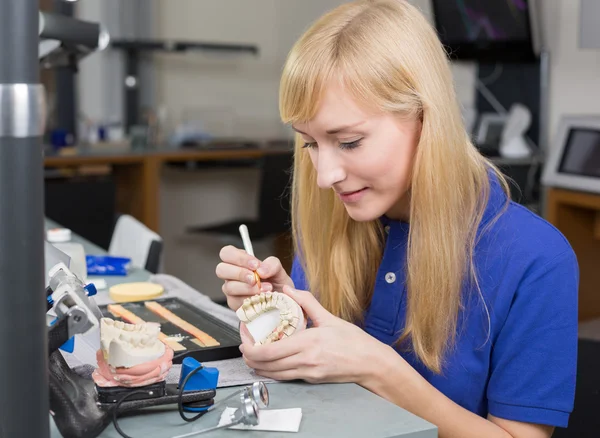 Dental lab technician applying porcelain to dentition mold — Stock Photo, Image