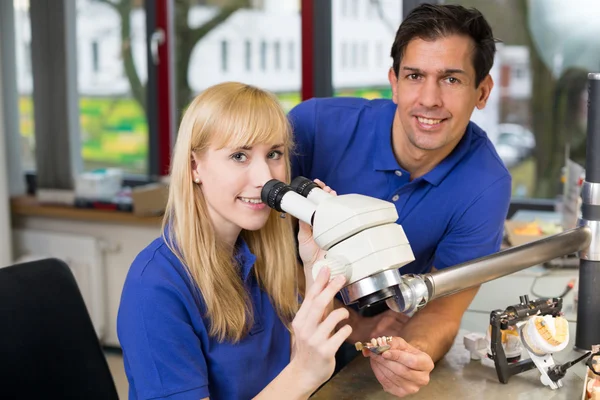Aprendiz e técnico odontológico ao microscópio — Fotografia de Stock