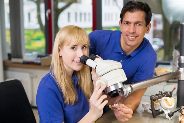 Lehrling und Zahntechniker am Mikroskop — Stockfoto