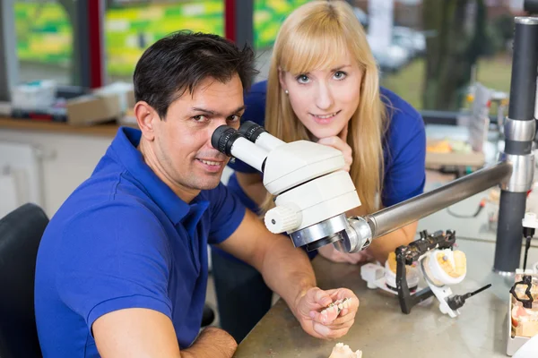 Técnicos dentales trabajando en microscopio —  Fotos de Stock