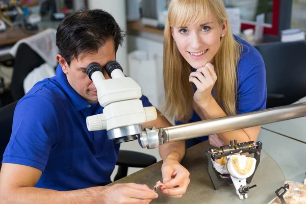 Técnicos odontológicos trabalhando em microscópio — Fotografia de Stock
