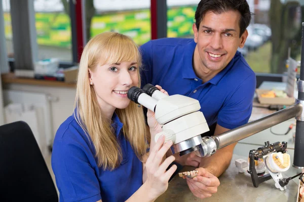 Lehrling und Zahntechniker am Mikroskop — Stockfoto