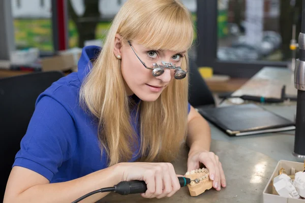 Dental technician with surgical loupes polishing gold tooth — Stock Photo, Image