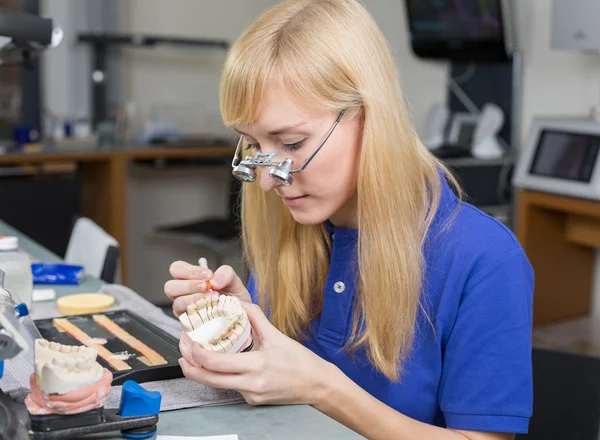 Técnico de laboratório odontológico aplicando porcelana ao molde de dentição — Fotografia de Stock