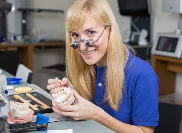 Técnico de laboratório odontológico aplicando porcelana ao molde de dentição — Fotografia de Stock