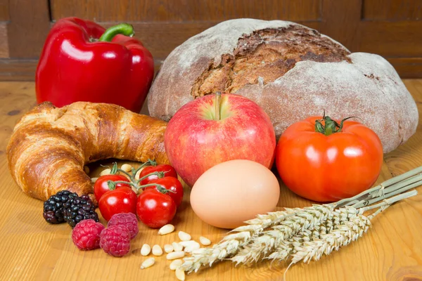 Konyhaasztal, sok élelmiszer, mint a kenyérrel és friss zöldségekkel — Stock Fotó