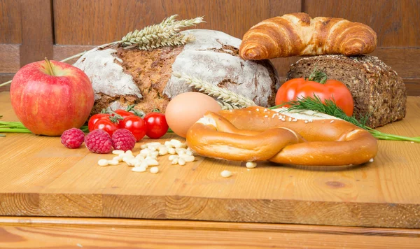 Mesa de la cocina con una gran cantidad de alimentos como pan y verduras — Foto de Stock