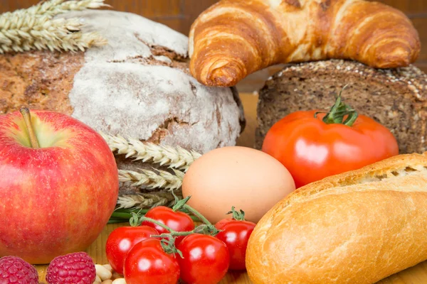 Кухонный стол с большим количеством еды, как хлеб и овощи — стоковое фото