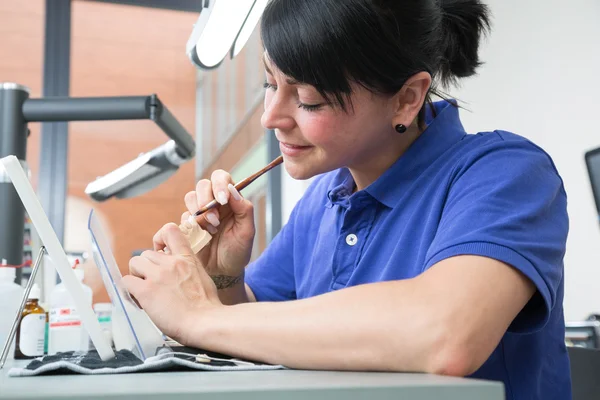 Technicus in een tandheelkundige laboratorium keramiek toe te passen op een prothese — Stockfoto