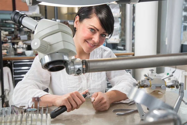 Technician in a dental lab or workshop working under a microscope — Stock Photo, Image