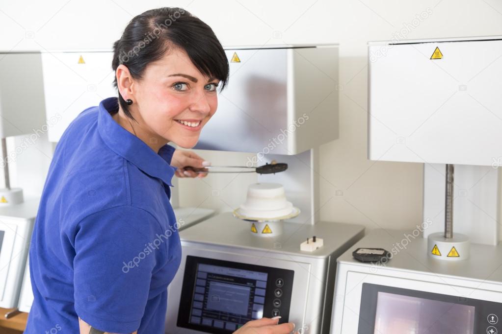 Dental technician in a laboratory taking ceramics out of the oven