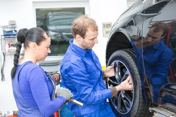 Two mechanics changing a wheel on a car — Stock Photo, Image