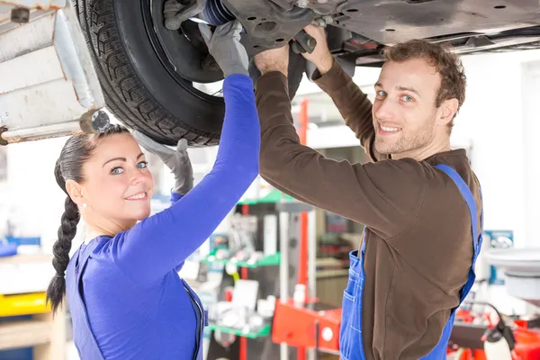 Två mekaniker reparera en bil i hydrauliska — Stockfoto