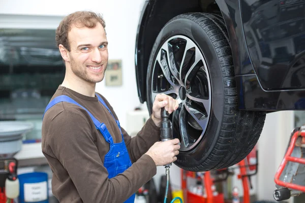 Mechaniker wechselt Räder an einem Auto auf hydraulischer Rampe — Stockfoto